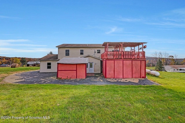 rear view of house featuring a pergola, a wooden deck, a storage shed, and a lawn