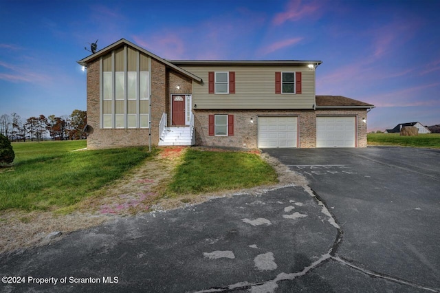 split foyer home featuring a lawn and a garage