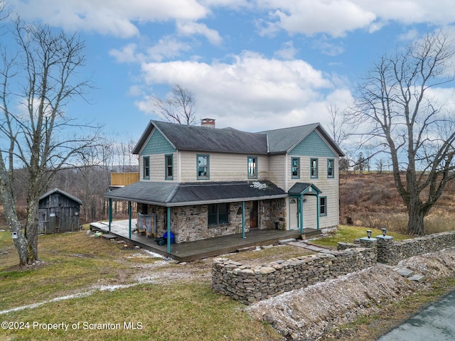 country-style home with a front lawn, covered porch, and a shed