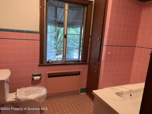 bathroom with radiator heating unit, vanity, and tile walls