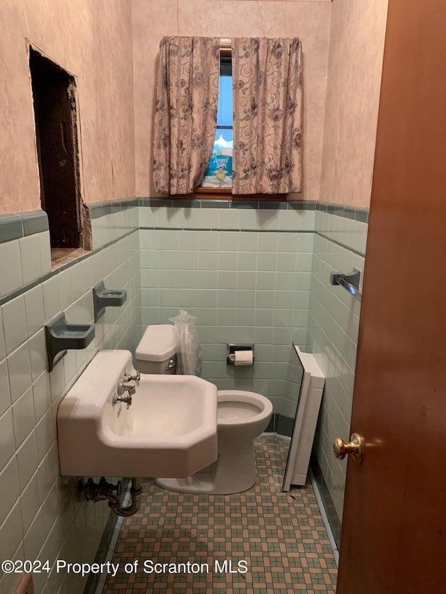 bathroom featuring tile patterned floors, sink, tile walls, and toilet