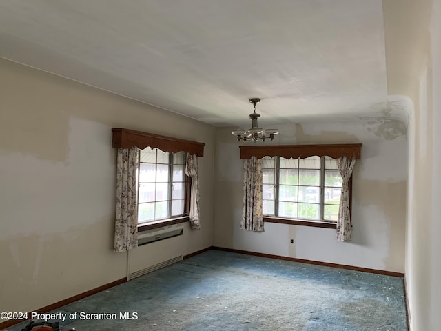 unfurnished room featuring carpet and an inviting chandelier