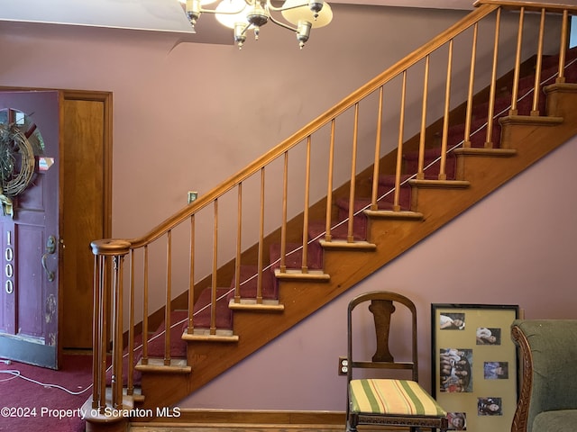 stairs with a notable chandelier