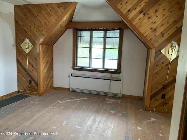 bonus room featuring wood walls, radiator heating unit, lofted ceiling, and hardwood / wood-style flooring