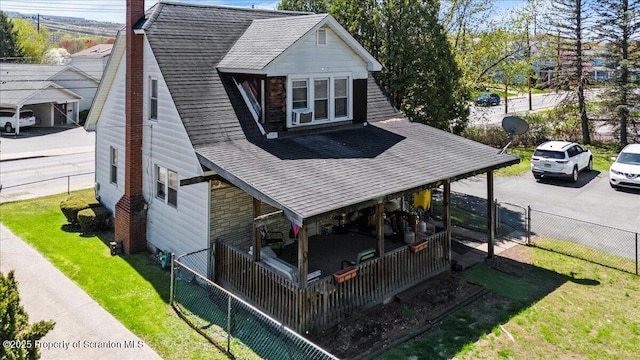 back of property with a lawn, a shingled roof, a fenced backyard, and a chimney