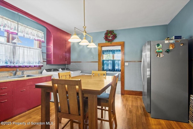 dining room featuring washing machine and dryer, wainscoting, wood finished floors, and radiator
