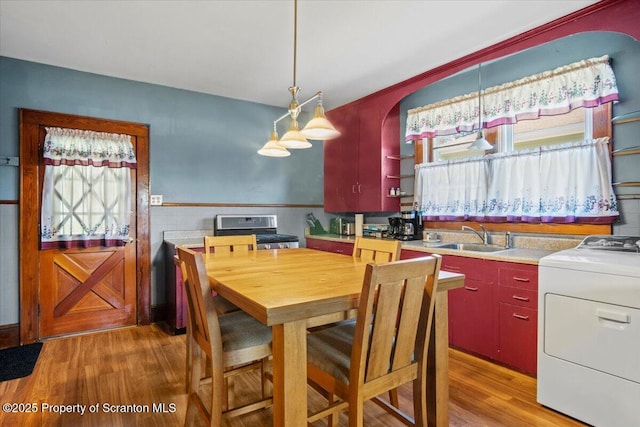 dining room with washer / dryer, wainscoting, a wealth of natural light, and light wood finished floors