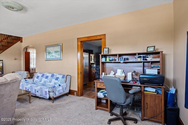 carpeted office with baseboards and arched walkways