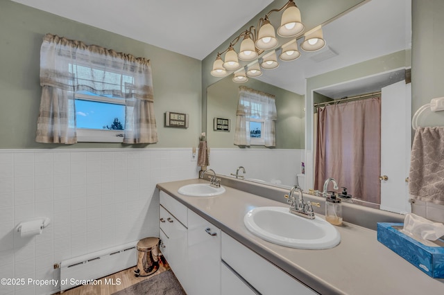 full bath featuring baseboard heating, tile walls, a wainscoted wall, and a sink