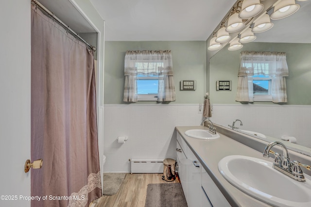 bathroom featuring a sink, a baseboard radiator, and a healthy amount of sunlight