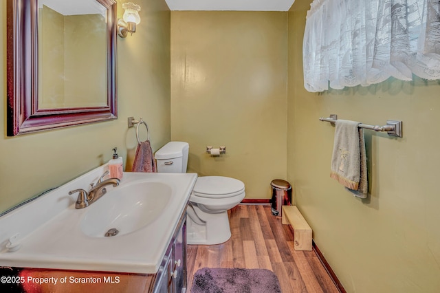 bathroom with vanity, toilet, wood finished floors, and baseboards