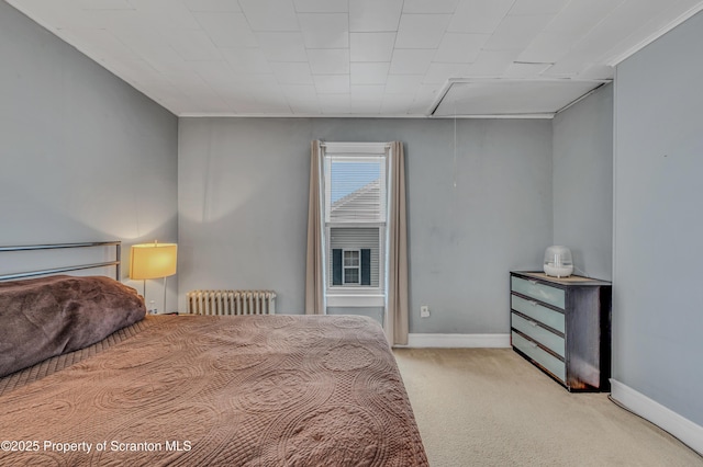 bedroom featuring baseboards, attic access, radiator heating unit, and carpet