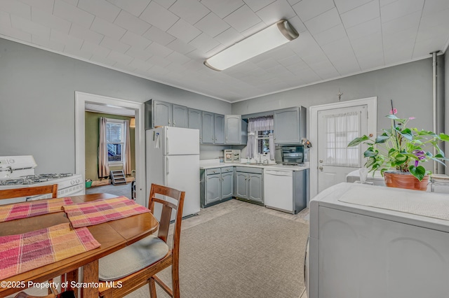 kitchen with white appliances, gray cabinetry, plenty of natural light, and washer / dryer