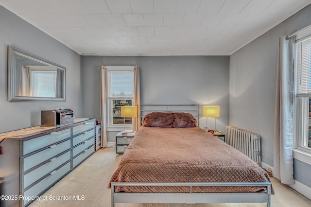 bedroom featuring light colored carpet, radiator, and baseboards