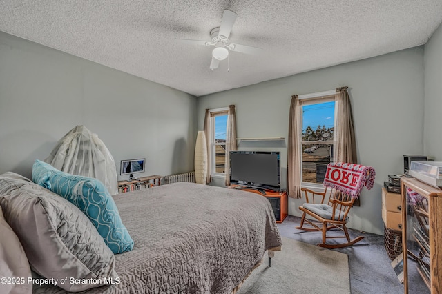 bedroom featuring ceiling fan, a textured ceiling, and carpet