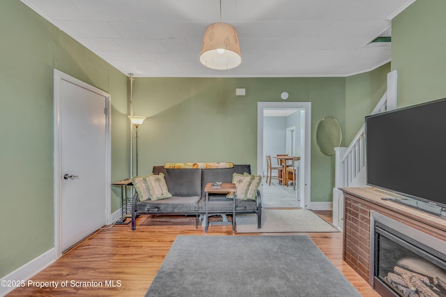 living room with crown molding, stairs, baseboards, and wood finished floors