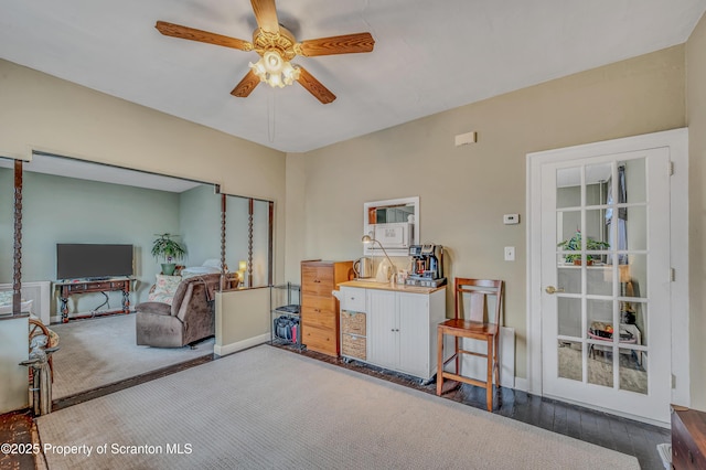 living area with wood finished floors, a ceiling fan, and baseboards