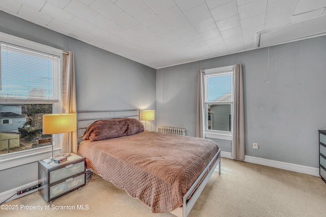 bedroom with baseboards, carpet, attic access, and radiator heating unit