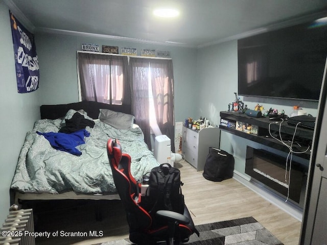 bedroom featuring radiator, ornamental molding, and wood finished floors