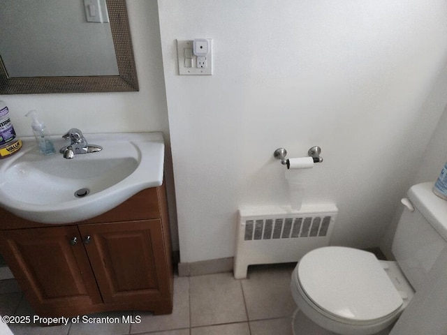 bathroom with radiator, toilet, vanity, tile patterned flooring, and baseboards