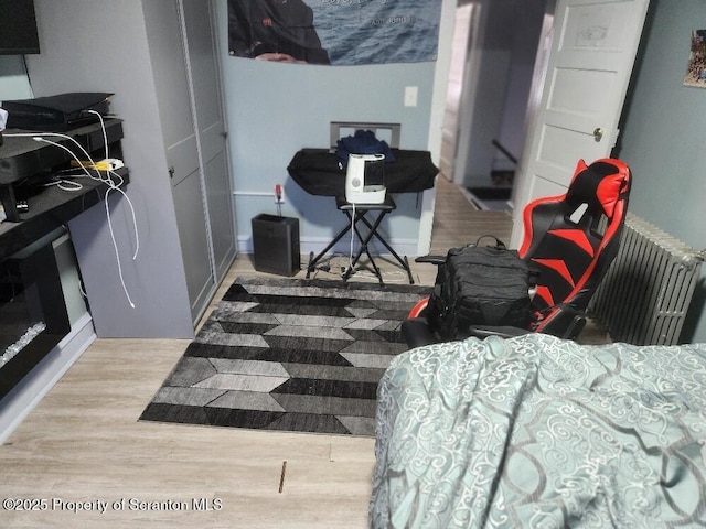 bedroom with baseboards, radiator heating unit, and wood finished floors