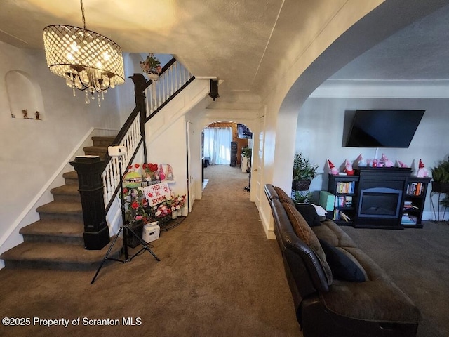 living area featuring arched walkways, carpet, a fireplace, stairway, and an inviting chandelier