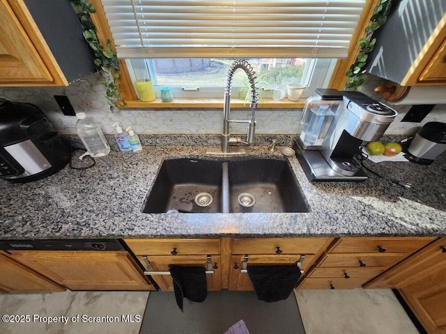 kitchen with stone countertops, a sink, and decorative backsplash