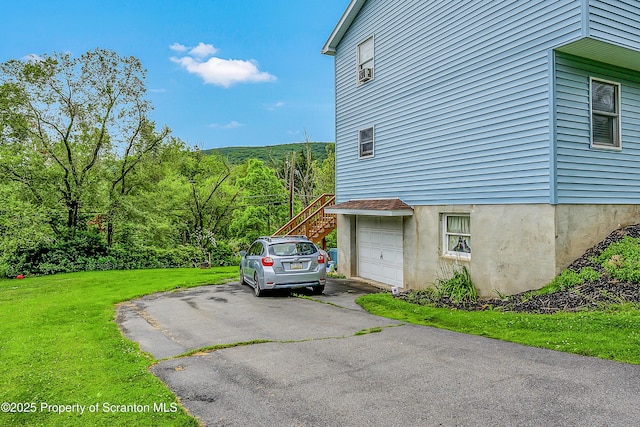119121 Fern Way S, Abington Twp, PA 18411 - view of side of home with asphalt driveway, a yard, an attached garage, and a forest view