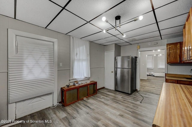 kitchen featuring light wood finished floors, a paneled ceiling, wood counters, and freestanding refrigerator