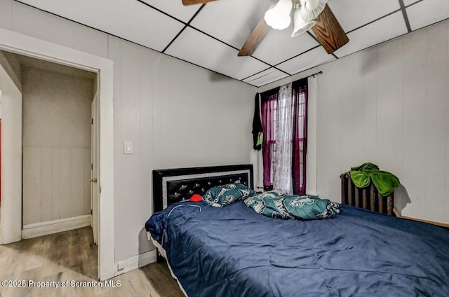 bedroom with a drop ceiling, baseboards, and wood finished floors