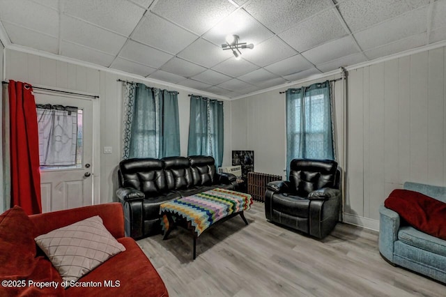 living room featuring ornamental molding, a drop ceiling, radiator heating unit, and wood finished floors