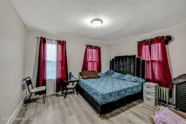 bedroom featuring radiator heating unit, wood finished floors, and baseboards