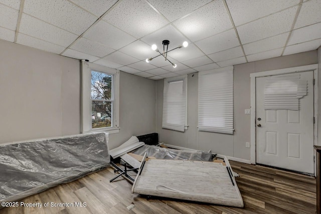 interior space featuring a chandelier, wood finished floors, a paneled ceiling, and baseboards