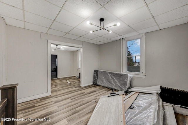 interior space featuring an inviting chandelier, wood finished floors, a paneled ceiling, and baseboards