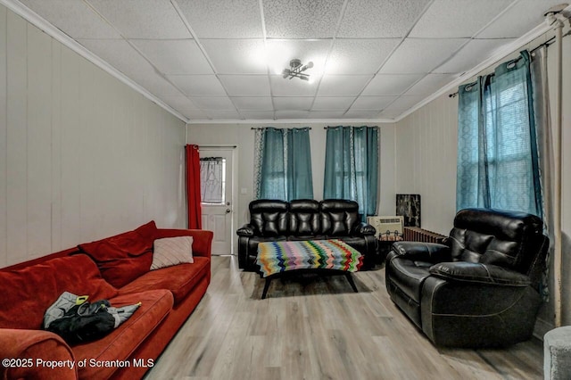 living room featuring ornamental molding, a drop ceiling, and wood finished floors