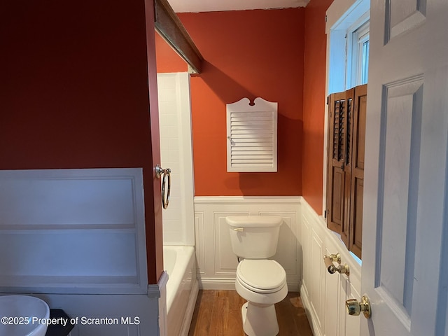 bathroom featuring hardwood / wood-style flooring, toilet, and a bathing tub