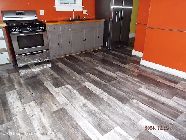 kitchen with dark hardwood / wood-style floors, stainless steel range with gas cooktop, gray cabinetry, and sink