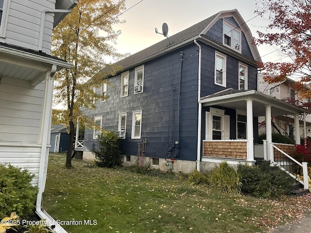 property exterior at dusk with a lawn and covered porch