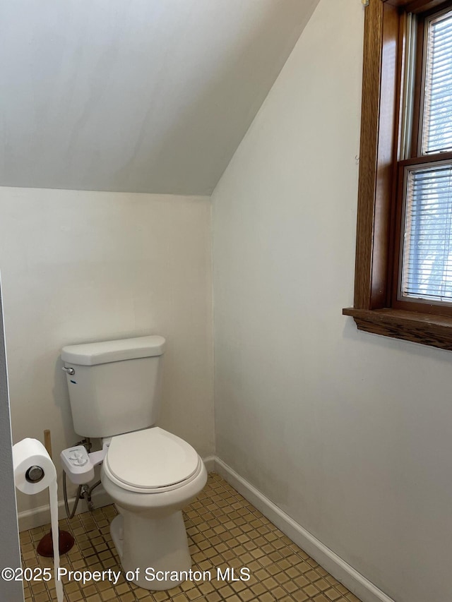 bathroom with tile patterned flooring, toilet, and vaulted ceiling