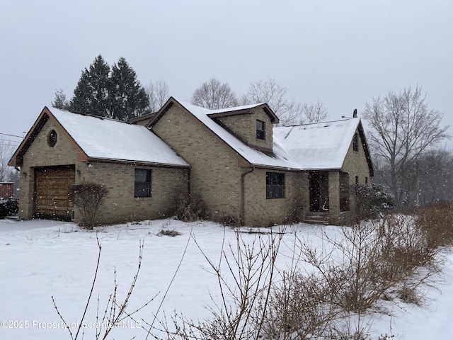 snow covered property with brick siding