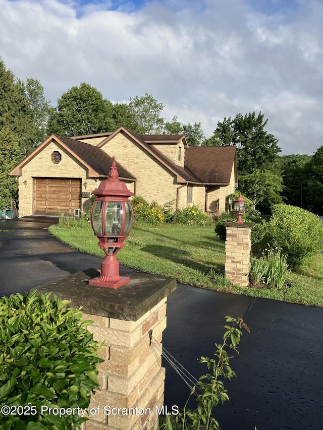 view of front of house featuring a garage, a front lawn, and brick siding