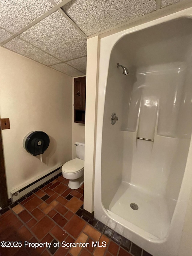 full bath featuring brick floor, toilet, a paneled ceiling, baseboard heating, and walk in shower