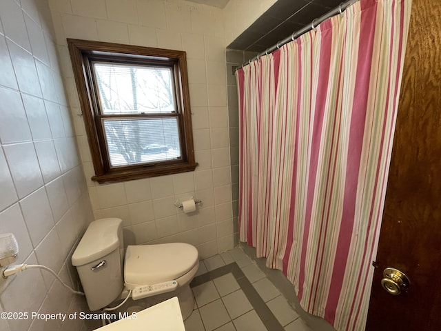 bathroom featuring toilet, a shower with shower curtain, tile patterned flooring, and tile walls