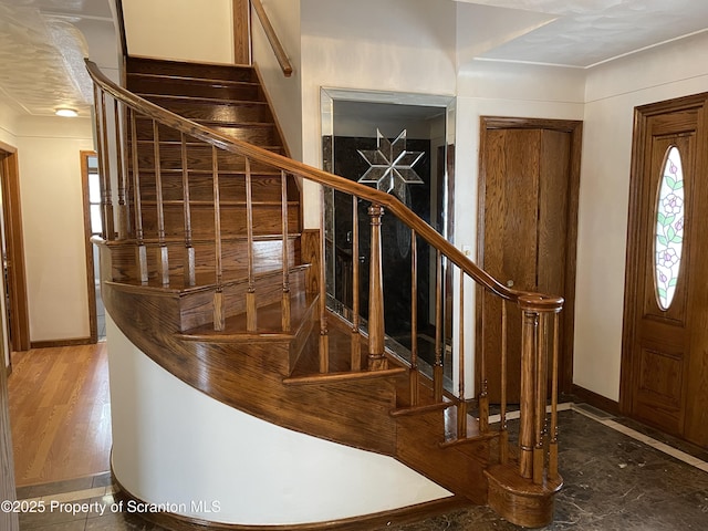 foyer featuring baseboards and stairs