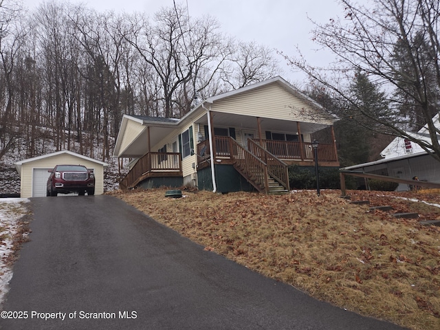 view of front facade featuring an outbuilding, stairway, driveway, covered porch, and a garage