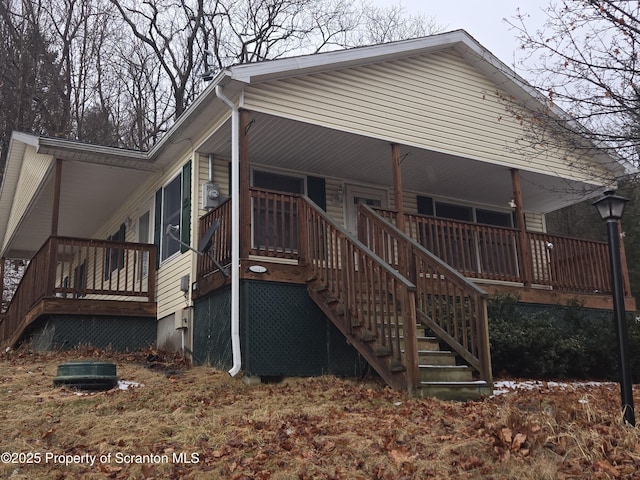 rear view of property featuring stairway and covered porch