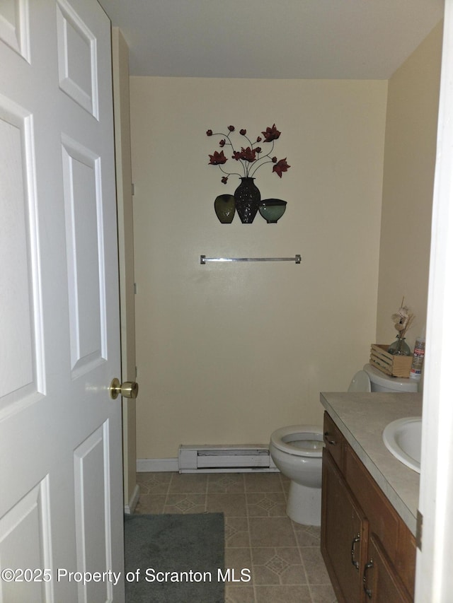 bathroom with a baseboard heating unit, toilet, vanity, and tile patterned flooring