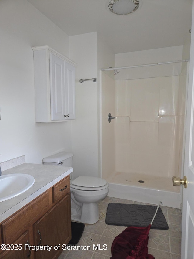 bathroom with a shower, toilet, vanity, and tile patterned floors