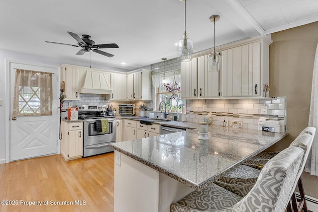 50 Humphrey St Unit 50-51, Old Forge, PA 18518 - kitchen featuring stainless steel appliances, custom range hood, a peninsula, a breakfast bar area, and dark stone counters
