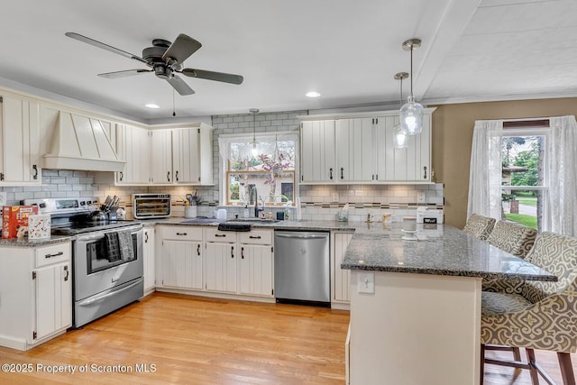 50 Humphrey St Unit 50-51, Old Forge, PA 18518 - kitchen featuring stainless steel appliances, a peninsula, a breakfast bar area, premium range hood, and light wood finished floors
